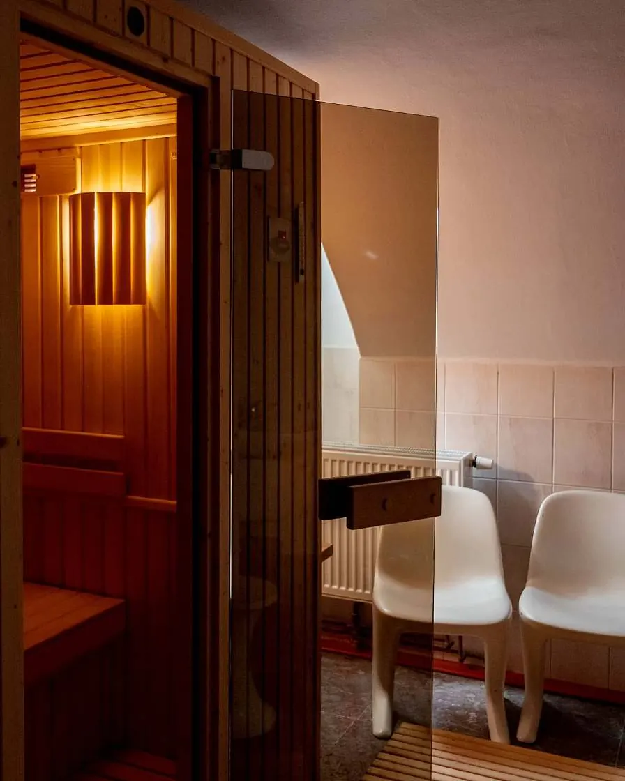 Infrasauna Peklíčko s rozsvíceným světlem a otevřenými dveřmi, vedle křesla odpočívárny