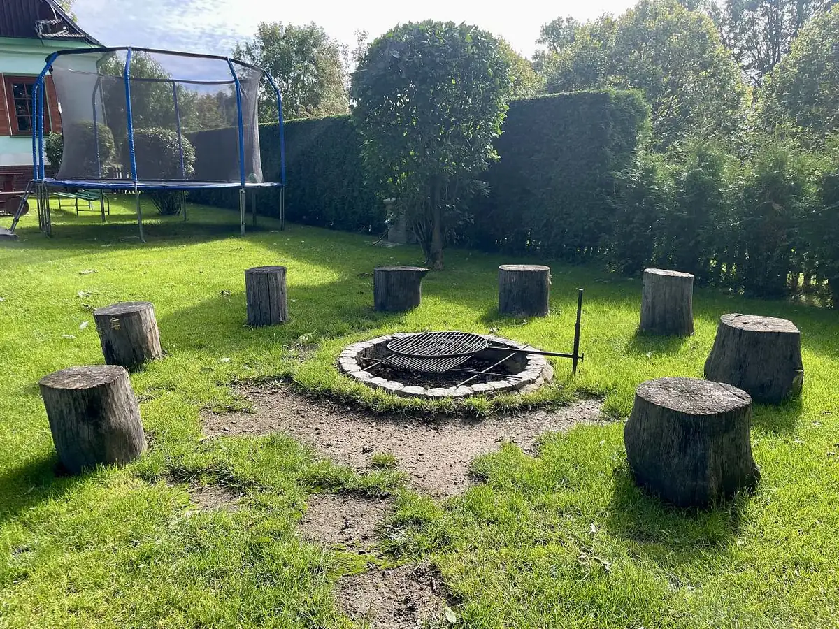 Ohniště s pařezy na zahradě, v pozadí trampolína